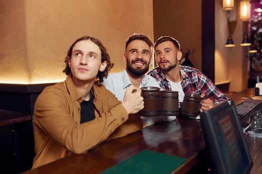 Sitting and, smiling.. Three friends are in the bar drinking beer and having a good time photo