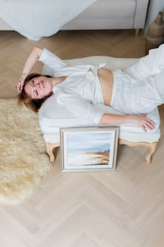 A woman is lying on a sofa in a stylish, bright living room next to a beautiful picture she painted herself photo