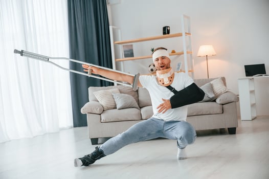 Positive man, with crutches is at home indoors dancing, having fun. Having injuries photo