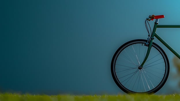 A minimalist bicycle resting against a smooth blue wall, surrounded by lush green grass photo