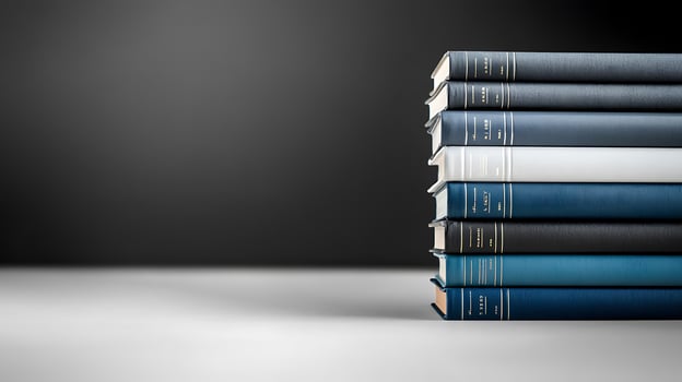 A neatly stacked collection of books in various shades against a minimalist dark background photo