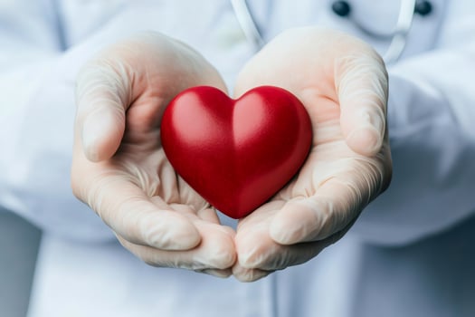 Doctor wearing latex gloves holding red heart symbol of health and care photo