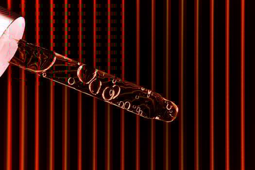 Serum in a pipette on a black and red ribbed background. photo