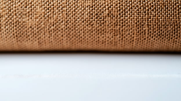 Close-up of textured fabric roll on a white surface with soft lighting, ideal for design use photo