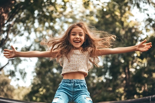 Happy girl jumping on trampoline, enjoying summer activity outdoors photo
