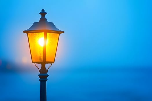 Illuminated Classic Street Lamp Post at Dusk Glowing Amber Light Blue Sky photo