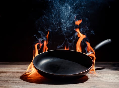Black cooking pan with flames placed in kitchen on dark background table... photo