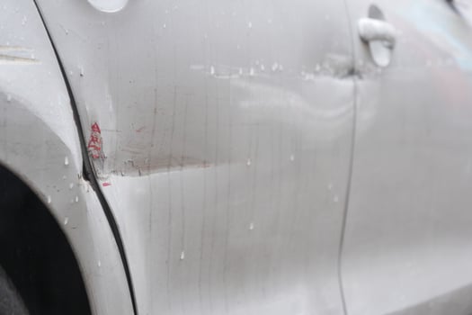 Vehicle with noticeable scratches and dents parked on city street photo