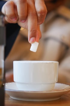 Sugar being added to a cup during a morning coffee break photo