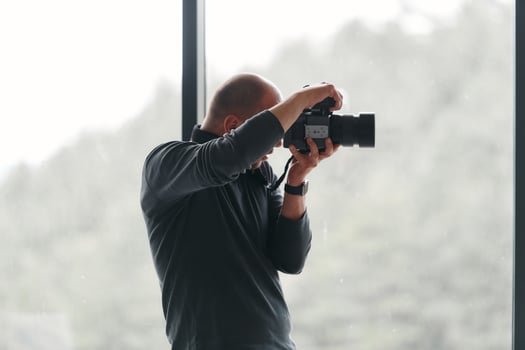 A professional photographer is captured working in his studio by a window, skillfully capturing a business photoshoot with precision and creativity. photo