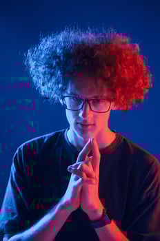 Red and blue colors. Young man with curly hair is indoors illuminated by neon lighting photo