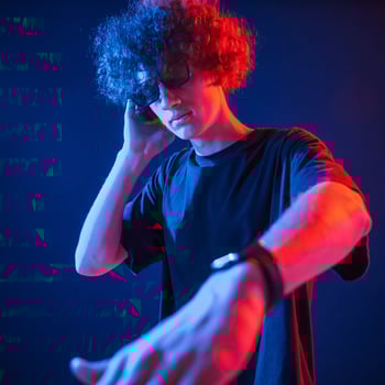 DJ is in the club. Young man. with curly. hair is indoors illuminated by neon lighting photo