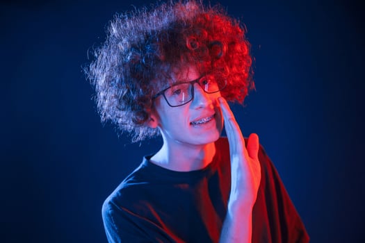 Conception of gossip. Telling ,a secret. Young man with curly hair is indoors illuminated by neon lighting photo