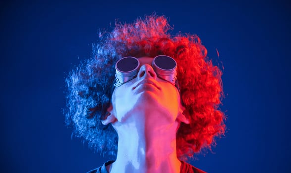 Portrait of young man with curly ,hair that is indoors illuminated by neon lighting. In retro eyewear photo