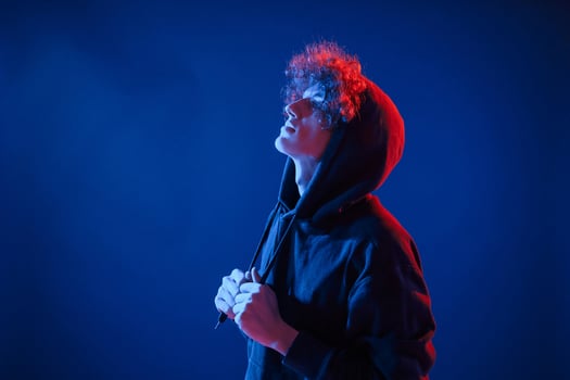 View from, the side. Young man with curly hair is indoors illuminated by neon lighting photo