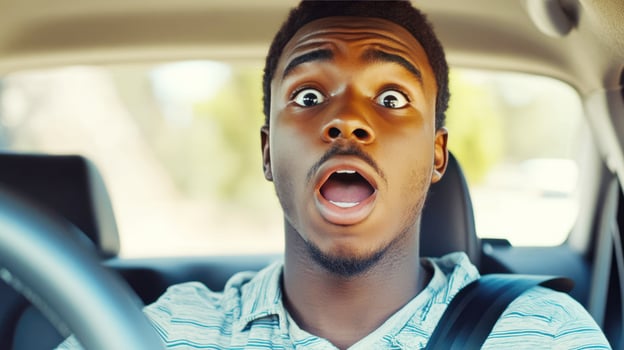 Man shows shock while driving a car in an unexpected moment during a sunny day photo