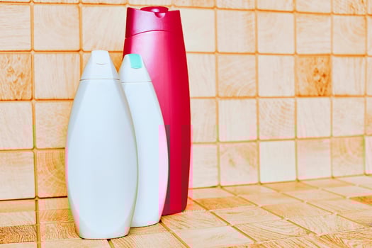 Plastic white red detergent bottles on tiled bath surface photo
