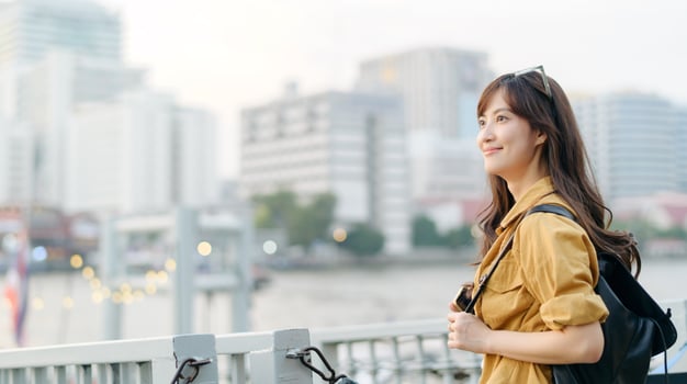 Asian woman standing on a bridge with city in background photo