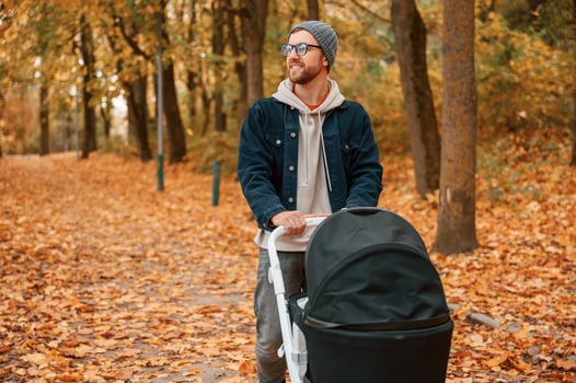 Enjoying the nature. Man, with pram is having a walk in the autumn park photo