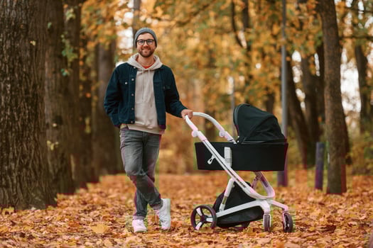 Standing and ,enjoying a nature. Man with pram is having a walk in the autumn park photo