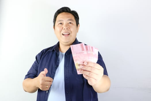 Asian man holding money and showing thumbs up photo