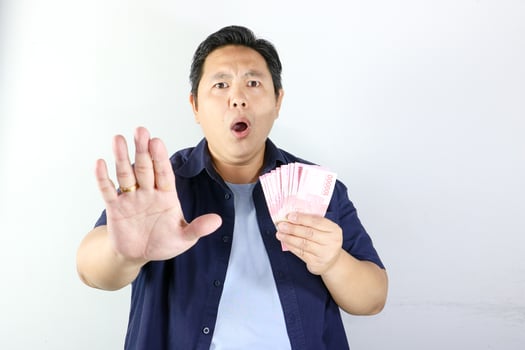 A man holding up money and making a stop sign photo