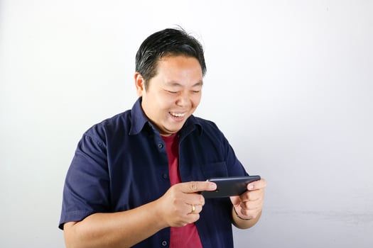 A man is smiling while holding a cell phone photo