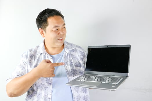 A man holding a laptop pointing at it photo