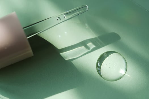 A drop of serum and dropper on a green background. photo