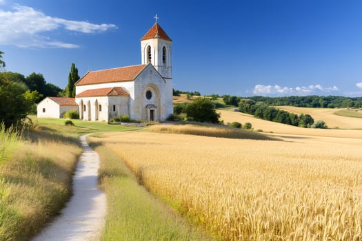 Path leading to charming church in beautiful wheat field during summer photo