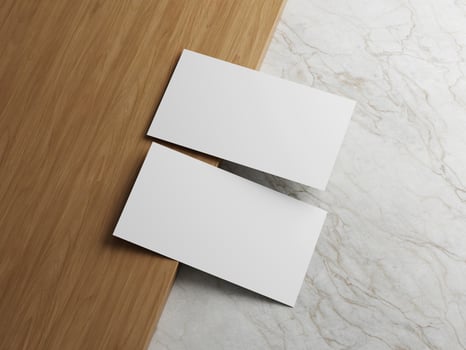 Two white business cards placed on a wooden surface with a marble background, offering a sleek and professional layout. photo