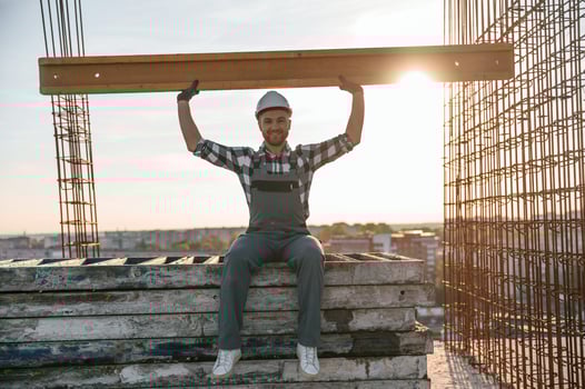 Sitting and ,holding wooden plank. Man is working on the construction site at daytime photo