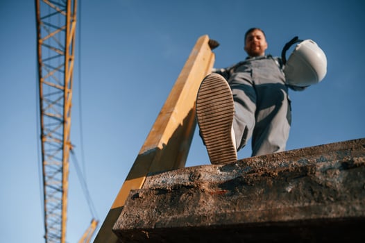 View from, below. With big wooden piece. Man is working on the construction site at daytime photo