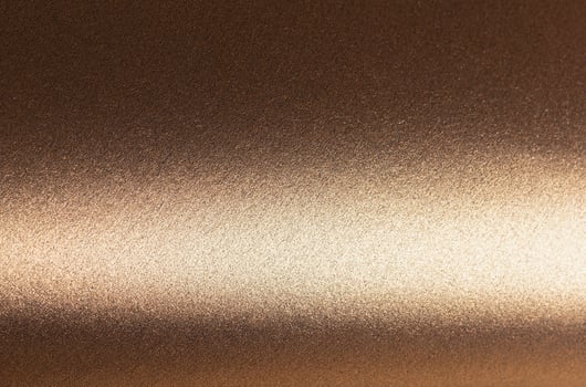 Elegant gold and bronze paper background with a smooth, pearlescent texture and shimmering metallic photo