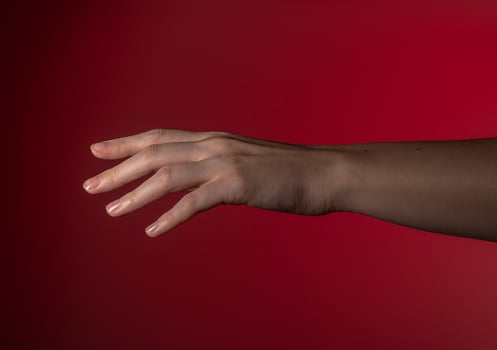 Hand reaching, fingers extended, gentle gesture. Woman's arm stretching, pinky out, soft motion in photo
