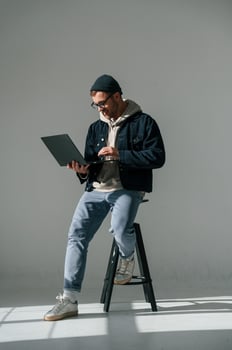 Sitting on ,the chair and holding laptop. Handsome man is in the studio against white background photo