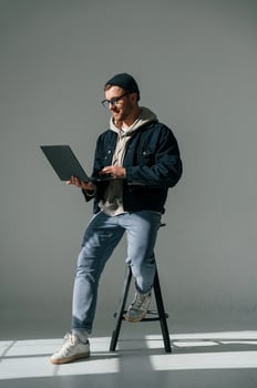 Sitting ,on the chair and, holding laptop. Handsome man is in the studio against white background photo
