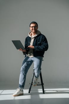 Sitting ,on the ,chair and holding laptop. Handsome man is in the studio against white background photo