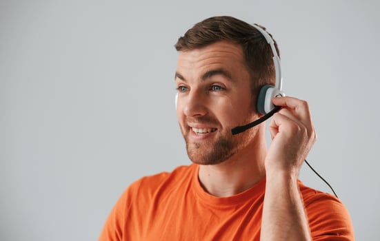 Talking to customers in headset.. Handsome man is in the studio against white background photo