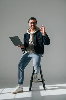 Sitting on the ,chair and holding laptop. Handsome man is in the studio against white background photo