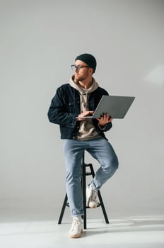 Modern silver, colored laptop in hands. Handsome man is in the studio against white background photo
