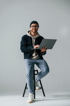 On the chair with laptop. Handsome man is in the studio against white background photo