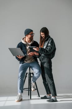 Beautiful man and woman, are together in the studio against background. With laptop and tablet in hands photo