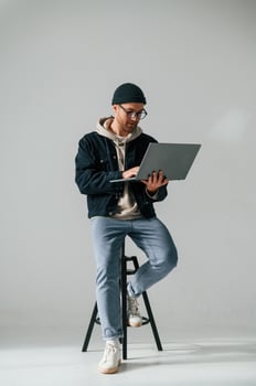 On,the chair with laptop. Handsome man is in the studio against white background photo