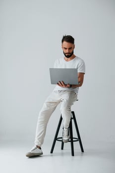On the chair with laptop. ,Handsome man is in the studio against white background photo