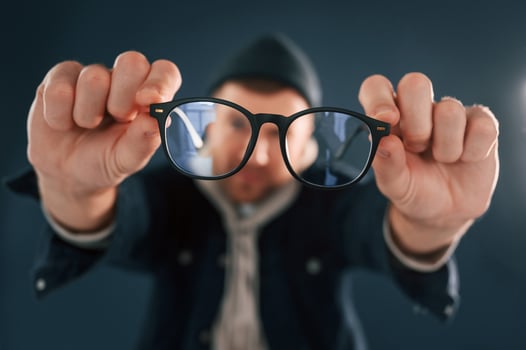 Funny guy playing with glasses. Handsome man is in the studio against blue background photo