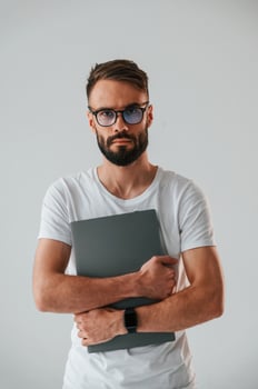 Silver colored laptop in hands.. Handsome man is in the studio against white background photo