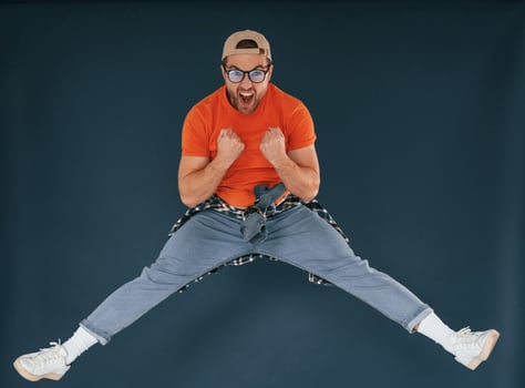 Jumping, feeling good, excited.. Handsome man is in the studio against blue background photo