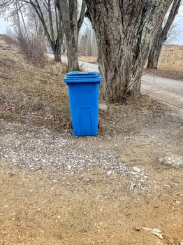 Blue Garbage Bin on Rural Gravel Path, Trees in Background, Outdoor Waste Management, Natural Setting. High quality photo