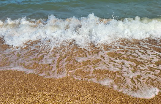 Beautiful azure sea with white foam and a beach on a clear sunny day photo